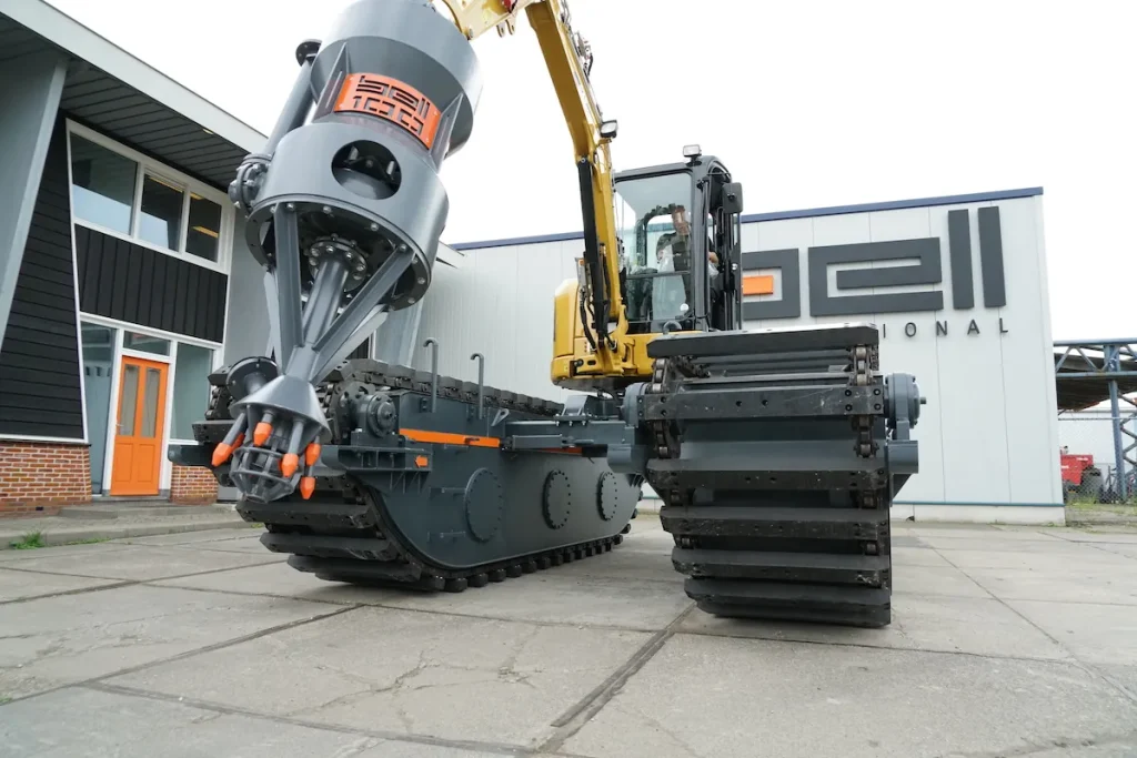 Excavadora anfibia « dredging », con pontones sobre orugas y brazo de grúa hidráulico, aparcada frente a las instalaciones de Bell Dredging Pumps.