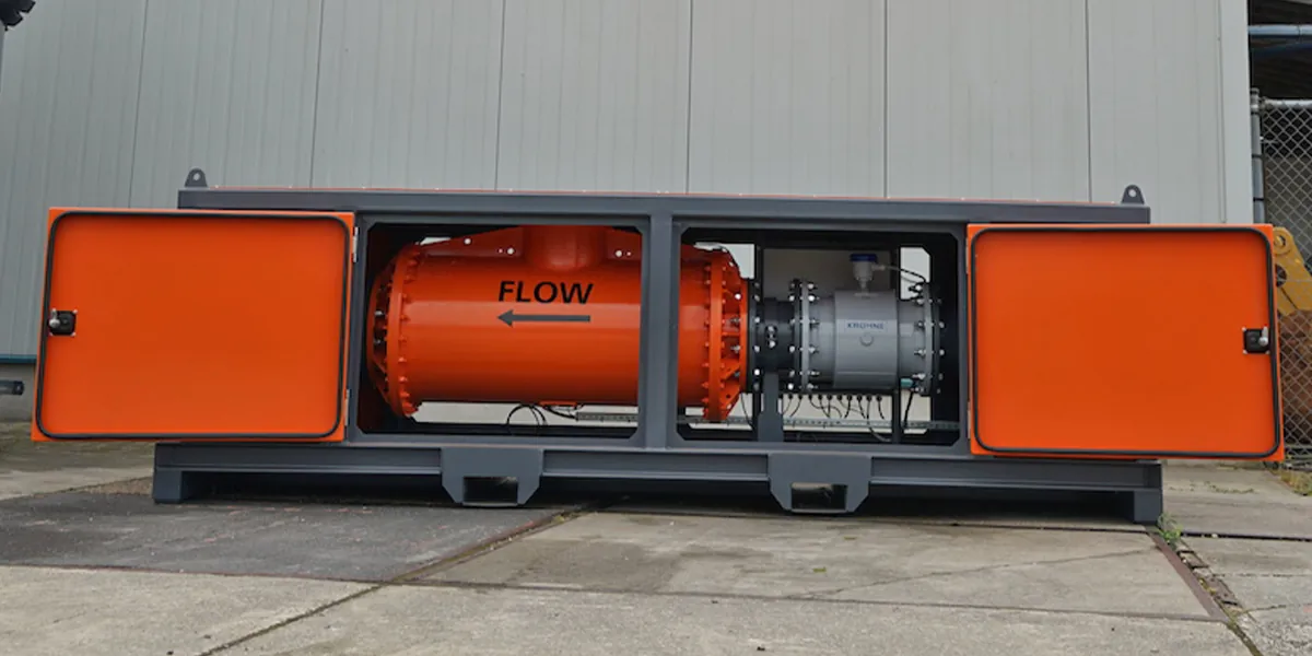 Skid-mounted flow meter unit with orange protective doors open, revealing an orange flow measurement pipe with 'FLOW' direction arrow and a Krohne meter, mounted on a gray steel frame skid.